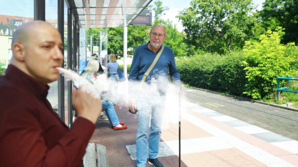 a man smoking a cigarette in front of a bus stop